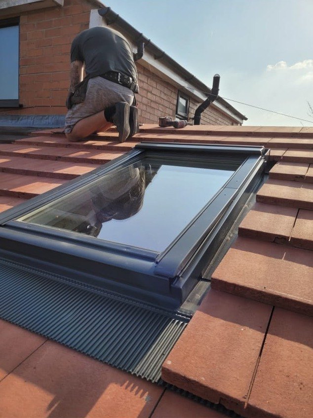 Roof window being fitted into a tiled pitched roof